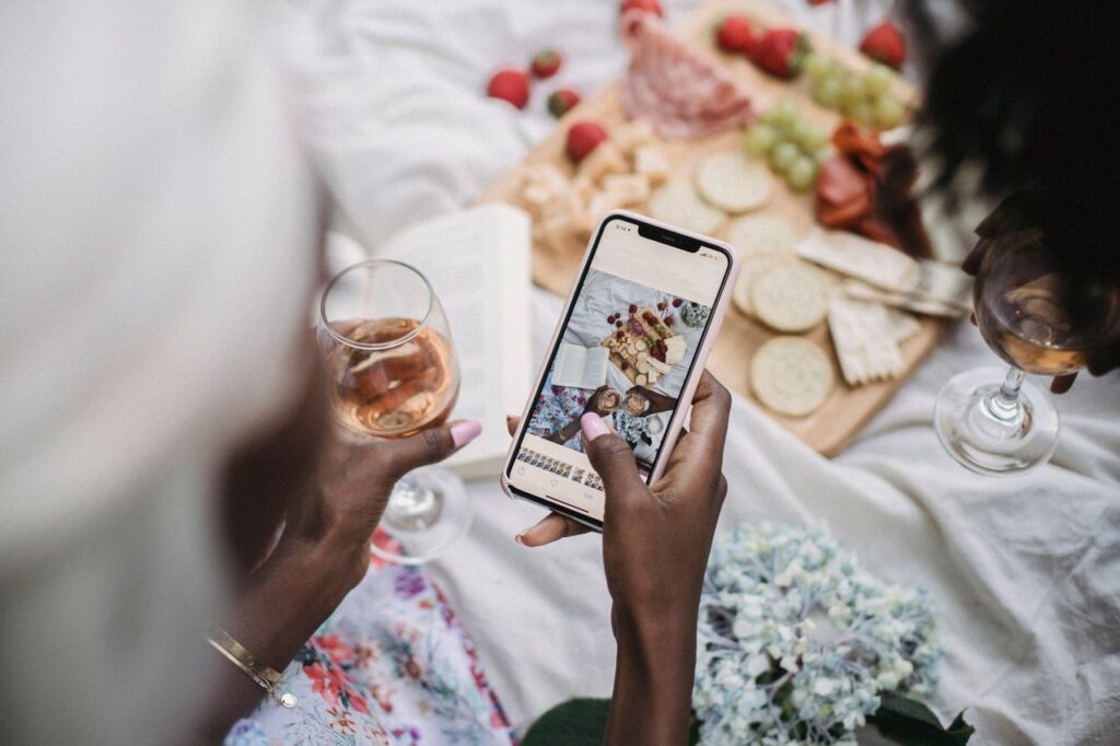 Overhead view of a picnic scene with people capturing moments using a smartphone.